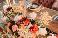 a bold fall wedding centerpiece of white, rust, orange and blush blooms, dried herbs and foliage