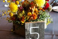 a bright fall floral centerpiece with greenery and a wooden table number for styling your tablescape