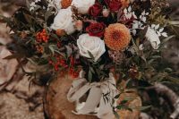 a bright fall wedding bouquet of white, orange, rust, deep red blooms, berries and lots of various foliage and leaves is wow