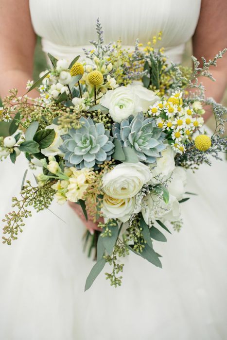 a bright wedding bouquet of white ranunculus, billy balls, chamomiles, greenery and succulents is a fun spring or summer wedding idea