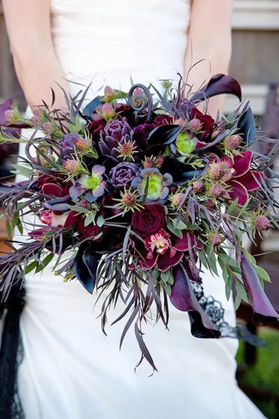 a catchy Halloween wedding bouquet with purple and burgundy blooms, greenery, thistles and foliage is wow