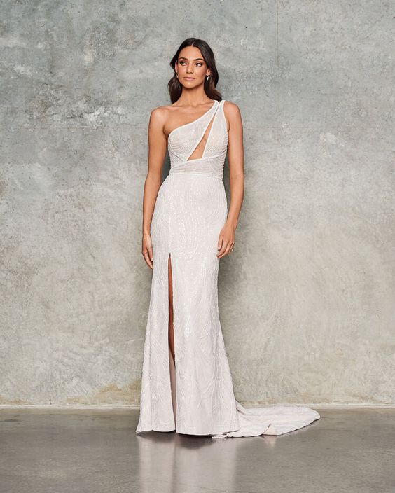 a catchy embellished mermaid wedding dress with a cutout one shoulder bodice, a front slit and a train is a chic and bold idea