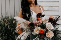 a catchy fall wedding bouquet of deep purple, neutral and rust blooms, greenery and pampas grass is an amazing textural arrangement for a fall boho bride