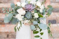 a chic and stylish wedding bouquet of white and blush ranunculus, greenery and green and purple succulents for summer