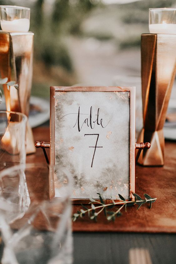 a copper frame with a table number and marble printing is a cool and bold idea for a fall wedding