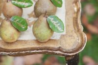 a creative fall wedding escort card display with leaves as cards – these pears can double as favors