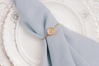 a delicate and subtle gold napkin ring with a circle and a rhinestone that matches the delicate serenity blue napkin