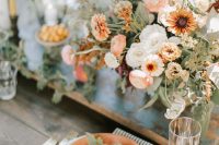 a delicate fall wedding centerpiece of orange and white blooms and lots of textural greenery