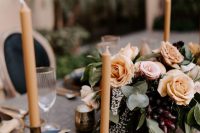 a delicate fall wedding centerpiece with blush and rust-colored blooms, greenery and grapes feels decadent