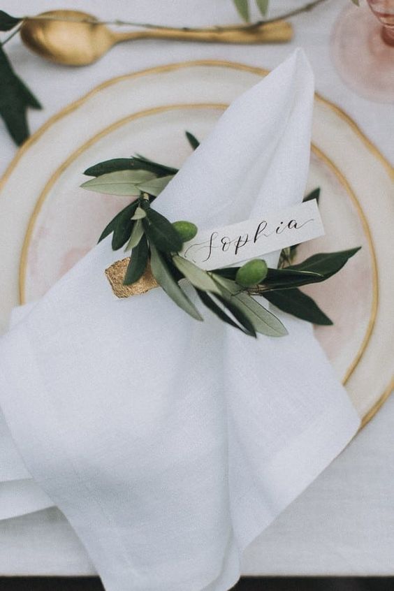 a delicate fresh greenery napkin ring with a gold dipped place card is a very modern and sophisticated idea to try