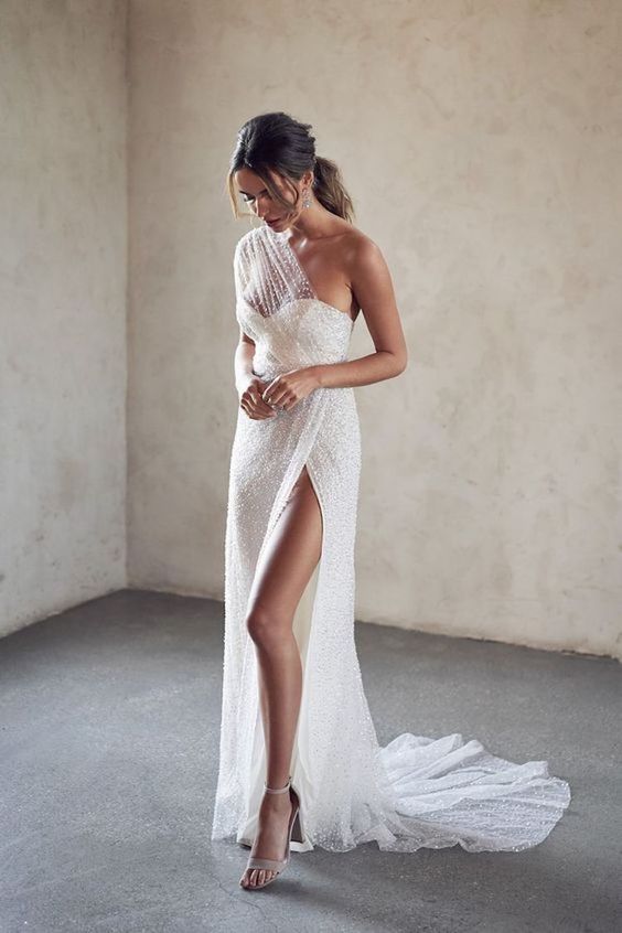 a fantastic embellished one shoulder wedding dress with an illusion neckline, a thigh high slit and a train looks ethereal