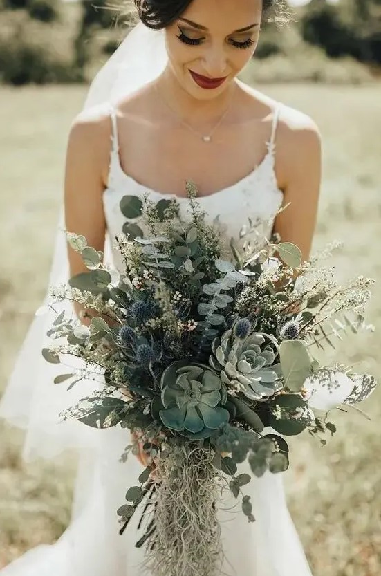 a fantastic greenery wedding bouquet with succulents, thistles and eucalyptus plus grasses for a woodland wedding