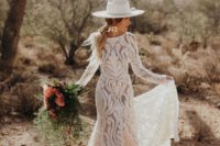 a fitting boho lace wedidng gown with a high neckline and long sleeves, statement earrings and a white hat for a boho elopement