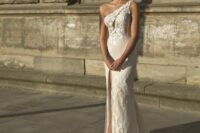 a floral lace one shoulder wedding dress with a cutout on the bodice, a thigh high slit on the front and a small train