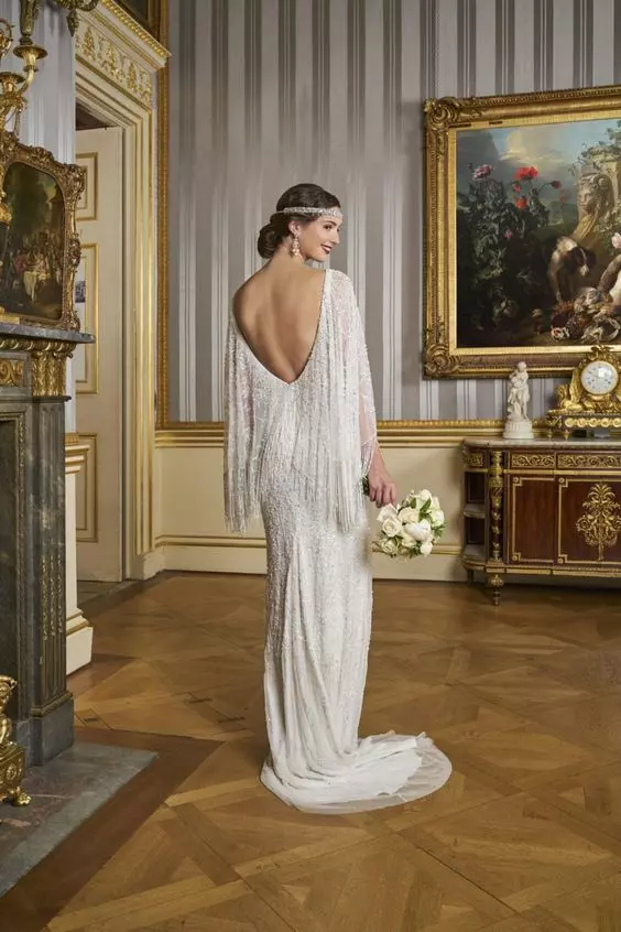 a fully embellished 1920s wedding dress with a cutout back, long fringe, a train, an embellished headband and statement earrings
