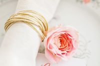 a gold cord and a pink flower are great as a delicate and chic accent to your tablescape, will do for a spring or summer wedding
