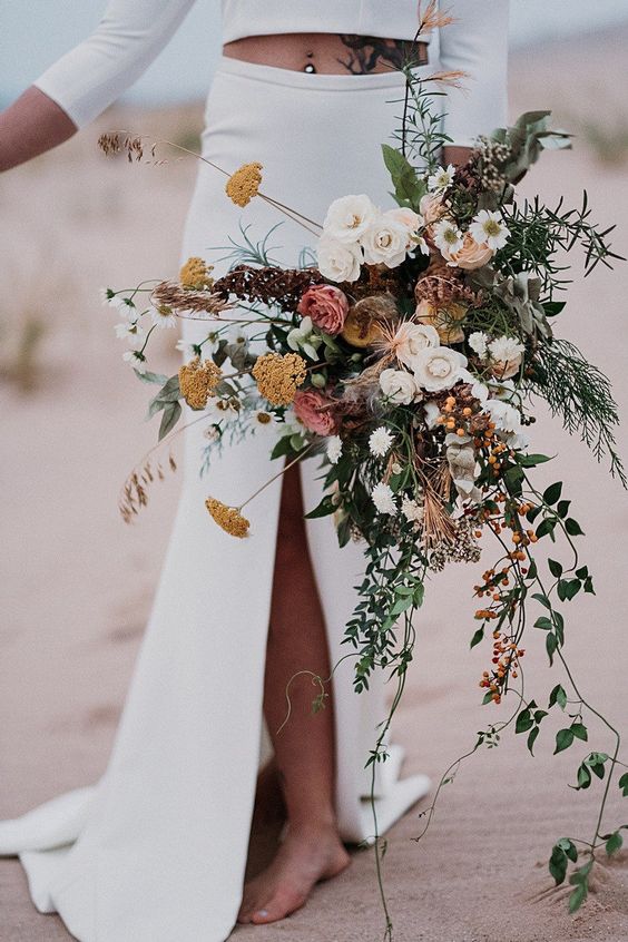 a gorgeous dimensional fall wedding bouquet of white, pink and rust blooms, greenery, berries, cascading branches and greenery is cool for a boho bride