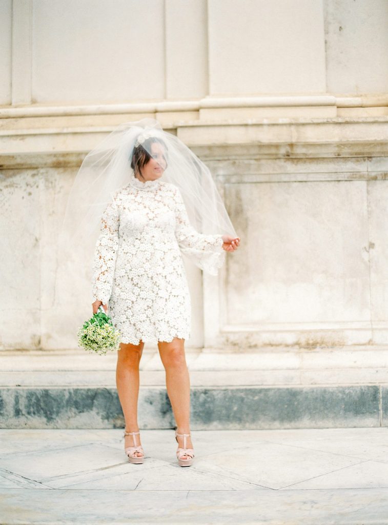 A lace A line wedding dress with a turtleneck, long sleeves, nude shoes and a veil for a retro inspired bride