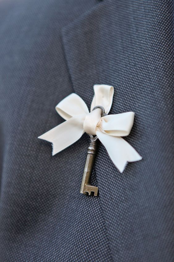 a little vintage boutonniere of a vintage key and a white ribbon bow is a gorgeous idea for a vintage wedding