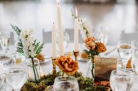 a lovely and chic fall wedding tablescape with a moss, white and rust blooms centerpiece, candles, white porcelain and glasses
