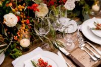 a lovely harvest wedding tablescape with bold blooms, berries, fruits, greenery, white plates and napkins, menus and cards