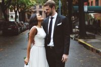 a modern A-line sleeveless wedding dress with a high neckline and a pleated skirt plus blue heels