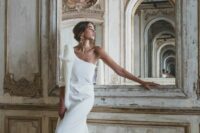 a modern exquisite plain A-line one shoulder wedding dress with a single long sleeve, a bow on the shoulder and a small train