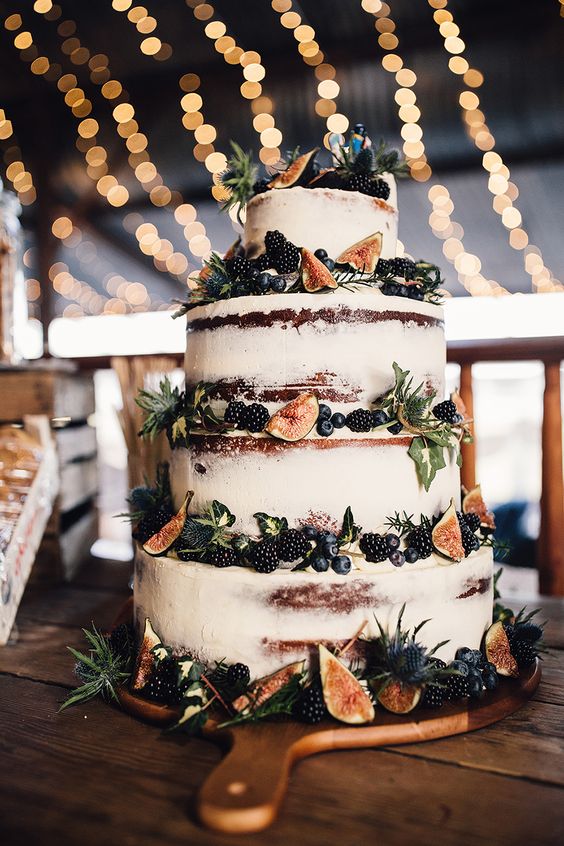 a naked fall wedding cake decorated with blackberries, blueberries, thistles and figs for a fall wedding