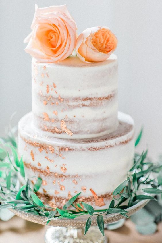 a naked wedding cake with copper leaf and blush roses and greenery is a very romantic piece