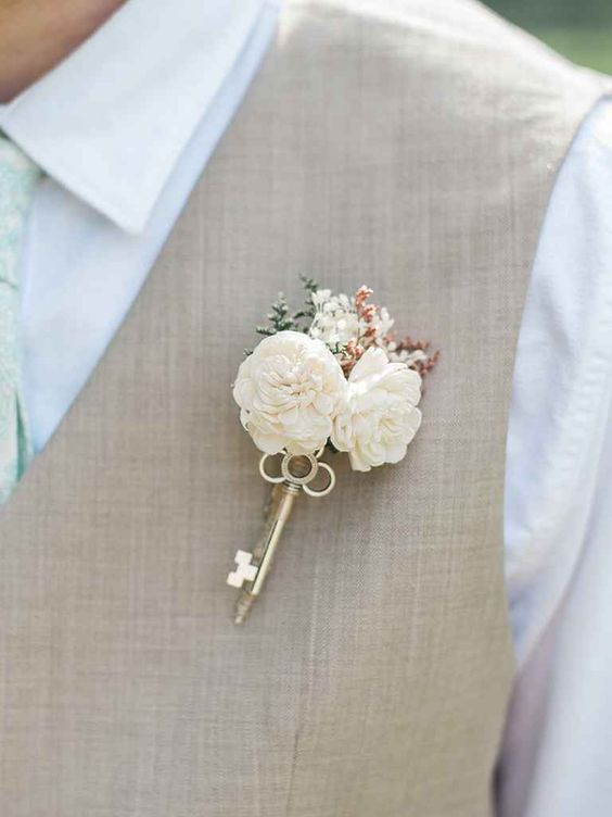a neutral vintage wedding boutonniere of neutral blooms, greeneyr and a vintage key will be a match for a vintage rustic groom's look