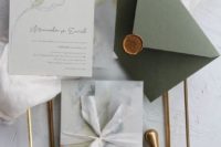 a neutral wedding invitation suite with marbleized invites and an olive green envelope with a seal