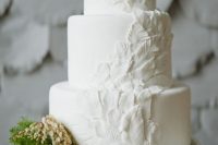 a plain white wedding cake decorated with sugar feathers is a unique idea for a modern wedding