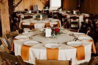 a pretty and simple rustic fall wedding tablescape with orange napkins, colorful blooms and greenery and a white tablecloth is cool