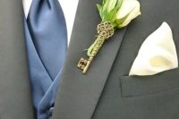 a pretty wedding boutonniere with a white rose, leaves and a vintage key is a lovely accessory for a groom or a groomsman