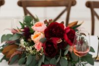 a purple napkin and a bold floral centerpiece with greenery, blush and peachy blooms plus burgundy ones for a touch of color