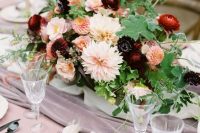 a refined autumn wedding centerpiece of leaves, blush, red and burgundy blooms is very elegant