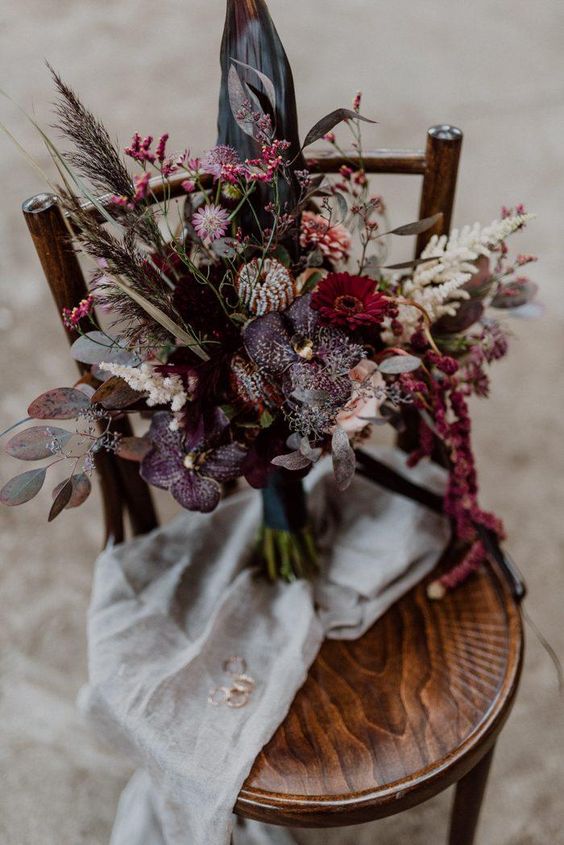 a refined dark fall wedding bouquet done with dark plum, hot pink and pink flowers, colored leaves and herbs for a boho wedding