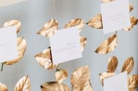 a refined fall wedding seating chart of net and gildede leaves and cards is a gorgeous idea