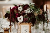 a refined moody floral centerpeice of purple, burgundy, white blooms and a chic framed table number