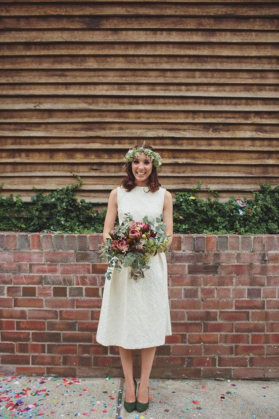 a retro-inspired lace A-line wedding dress with a high neckline, no sleeves and hunter green shoes