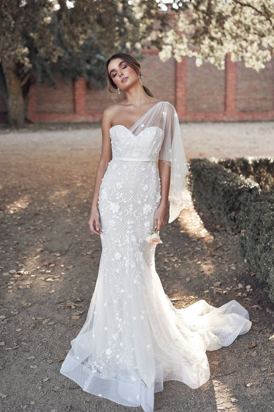 a romantic one shoulder mermaid wedding dress with floral lace applique, a short sleeve and a train for a romantic bride