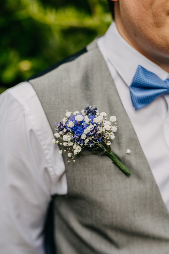 a simple and lovely wedding boutonniere of blue blooms and white baby's breath is a stylish idea for a vintage and rustic wedding