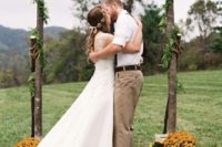 a simple outdoor fall wedding arch with grasses, leaves and blooms around for a backyard or rustic fall wedding