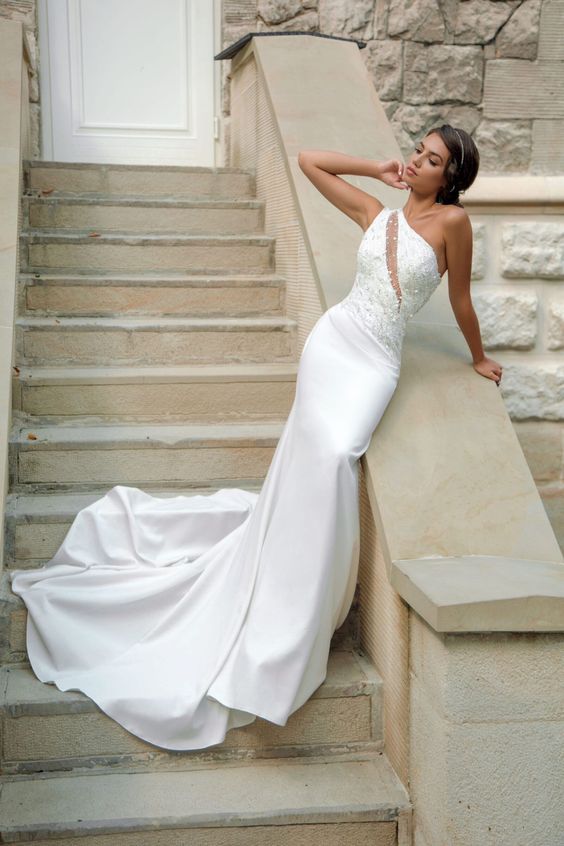 a sophisticated mermaid one shoulder wedding dress with an embellished bodice and an illusion cutout plus a train