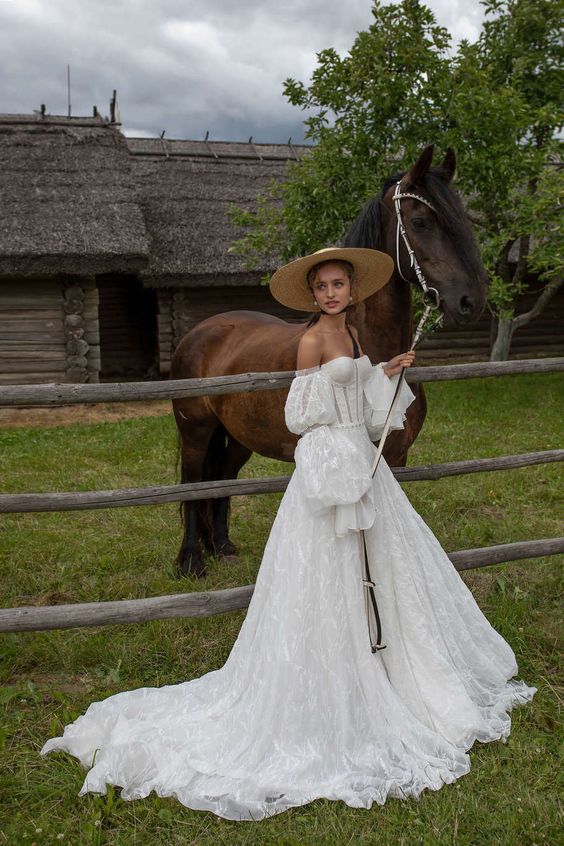 a strapless lace A-line wedding dress, puff sleeves, a train, a straw hat for a vintage rustic bridal look