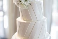 a striped white wedding cake topped with white blooms is a cool and timeless idea to rock