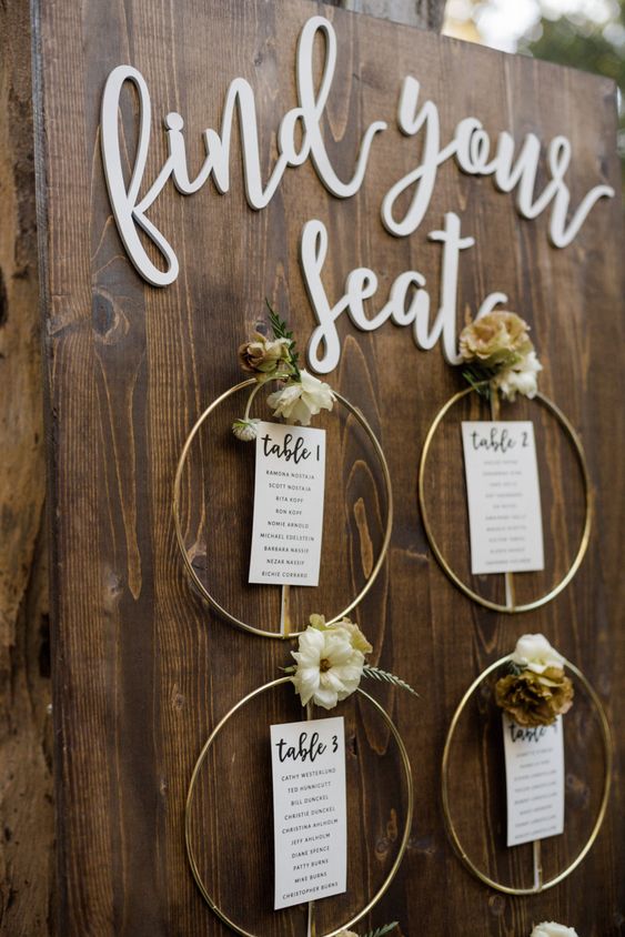 a stylish fall wedding seating chart with gilded embroidery hoops, cards and dried blooms and calligraphy