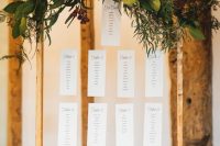 a stylish fall wedding seating chart with greenery, bright blooms, candles, himmeli and floating papers