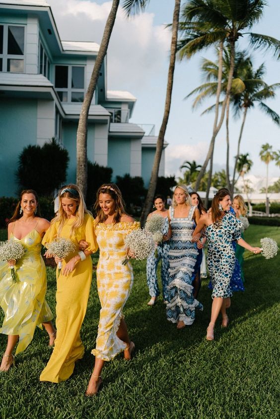 a super colorful and mismatching bridal party with yellow and blue bridesmaid dresses including a black thick strap striped one