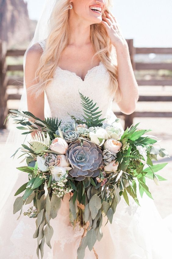 a super lush wedding bouquet of white and blush peony roses, greenery and foliage plus large succulents